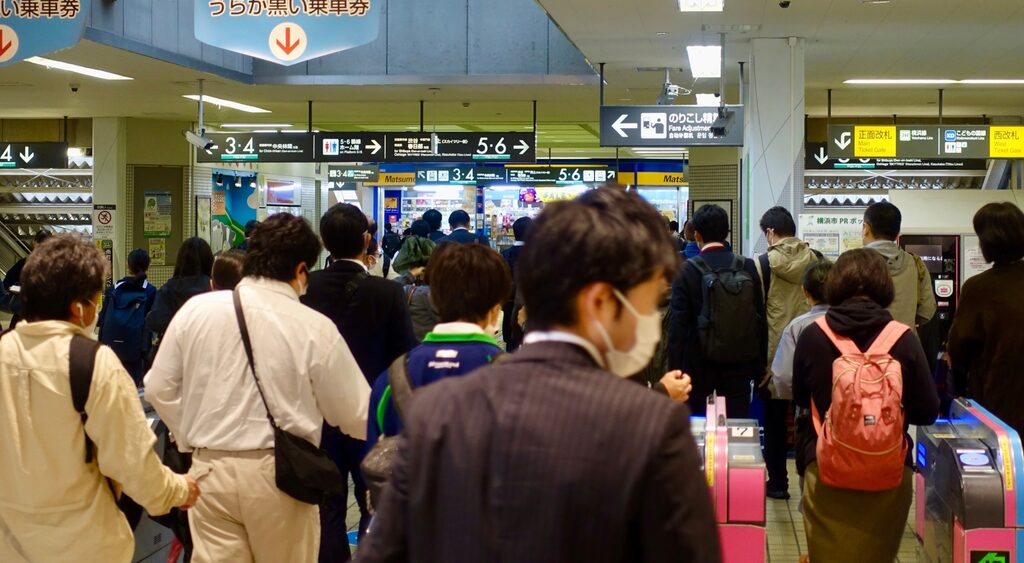 There are many passengers waiting on the platforms, in the waiting areas, and near the ticket gates.